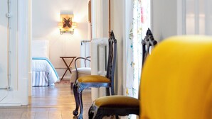 Une pièce avec un plancher en bois, un lit avec une literie à rayures, une chaise et une table.