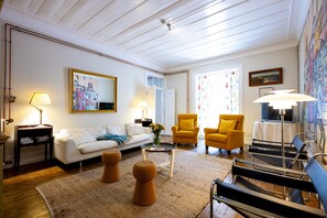 A living room with a white sofa, yellow armchairs, a coffee table, and a black sofa.