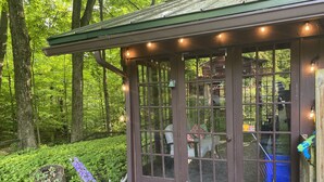 A wooden cabin with a porch, surrounded by lush greenery. - Quiet cottage nestled in the woods (Mount Gilead)