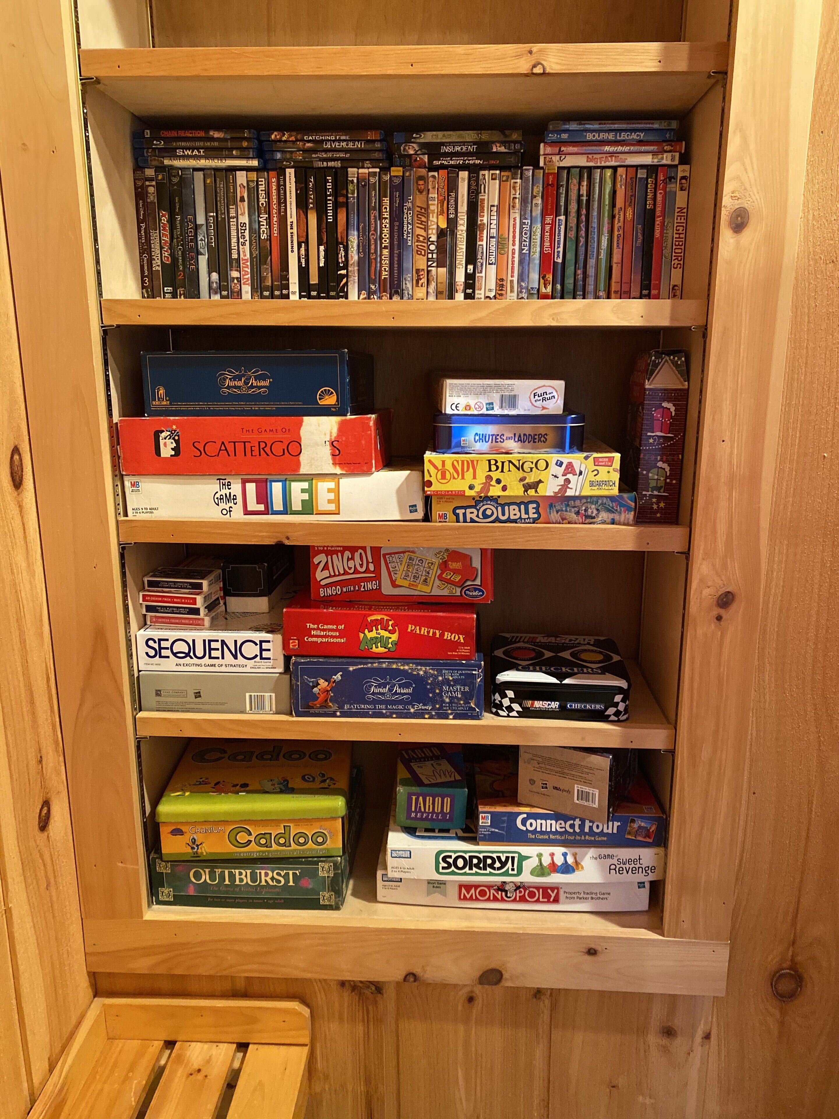 A wooden bookshelf with various board games and DVDs.