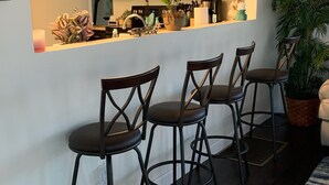 Una cocina con barra, taburetes de bar, microondas y una planta en maceta.