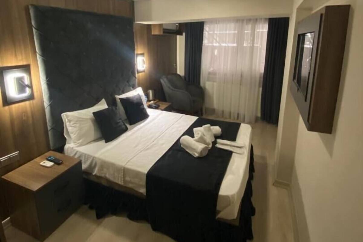 Una habitación de hotel con una cama grande, mesitas de noche, un escritorio y una silla.
