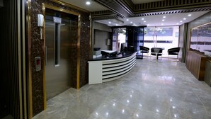 Ett modernt receptionsområde med ett marmorgolv, en böjd receptionsdisk och en glasvägg.