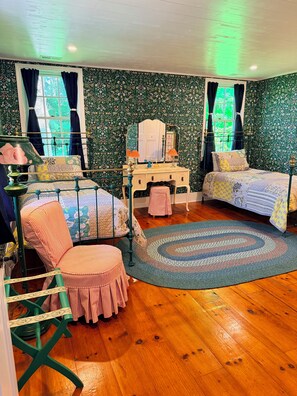Une pièce comprenant un lit, une chaise, une coiffeuse et un tapis à motifs.
