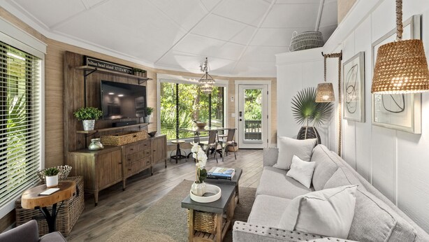 A spacious living room with a large TV, wooden cabinets, a dining area, and a sofa.