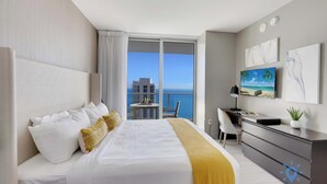 A modern hotel room with a large bed, a desk, and a view of the ocean. - High Floor 2BR|2 BA| Resort Fees & Parking Incl. (Hollywood)