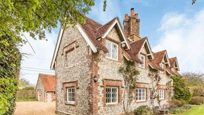 A stone house with a traditional design, featuring multiple chimneys and a well-maintained garden.