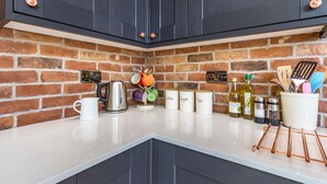 A kitchen with dark cabinets, a brick backsplash, and a white countertop.