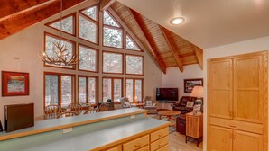 A spacious kitchen with a large island, wooden cabinets, and a high ceiling with exposed beams.