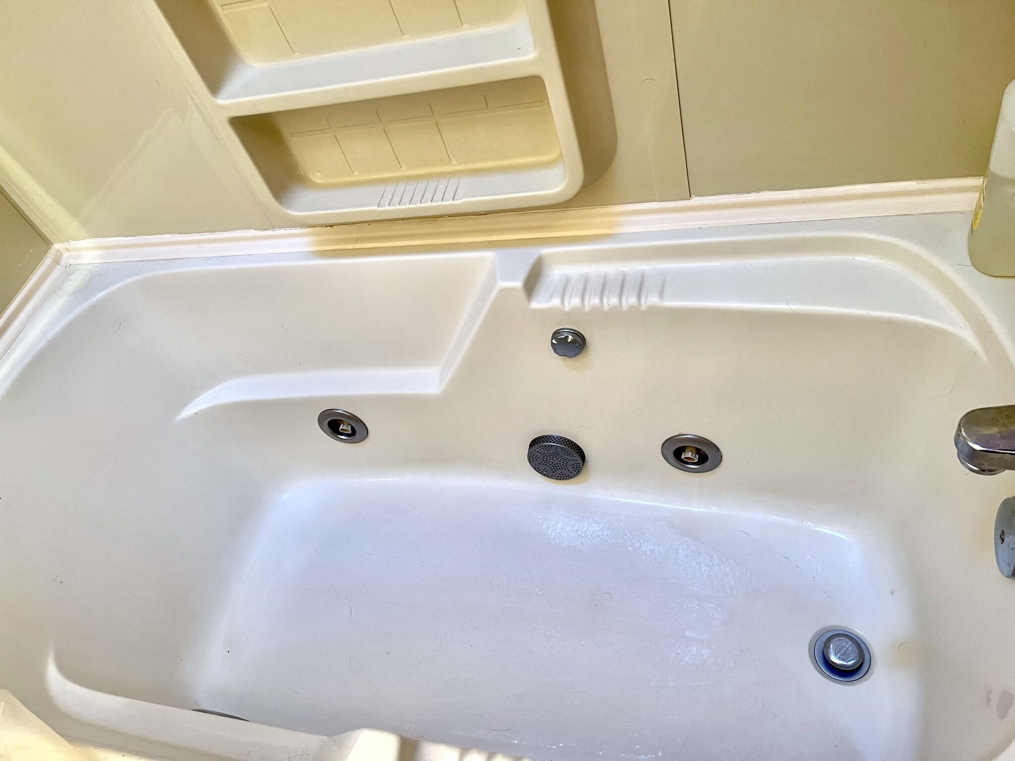 Una bañera blanca con tres grifos y un desagüe.