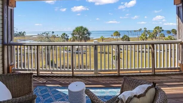 Un balcone con vista sulla spiaggia, arredi in vimini e un tappeto decorato.