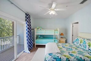 A bedroom with a bunk bed, a single bed, a ceiling fan, and a view of the outdoors.