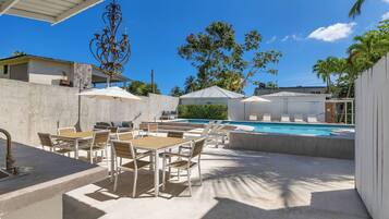 An outdoor pool area with lounge chairs and a dining setup.