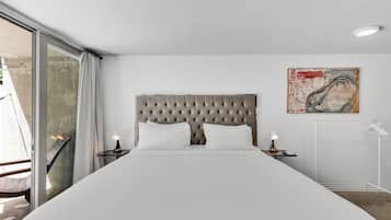 A modern bedroom with a tufted headboard, a large bed, two bedside lamps, and a painting on the wall.