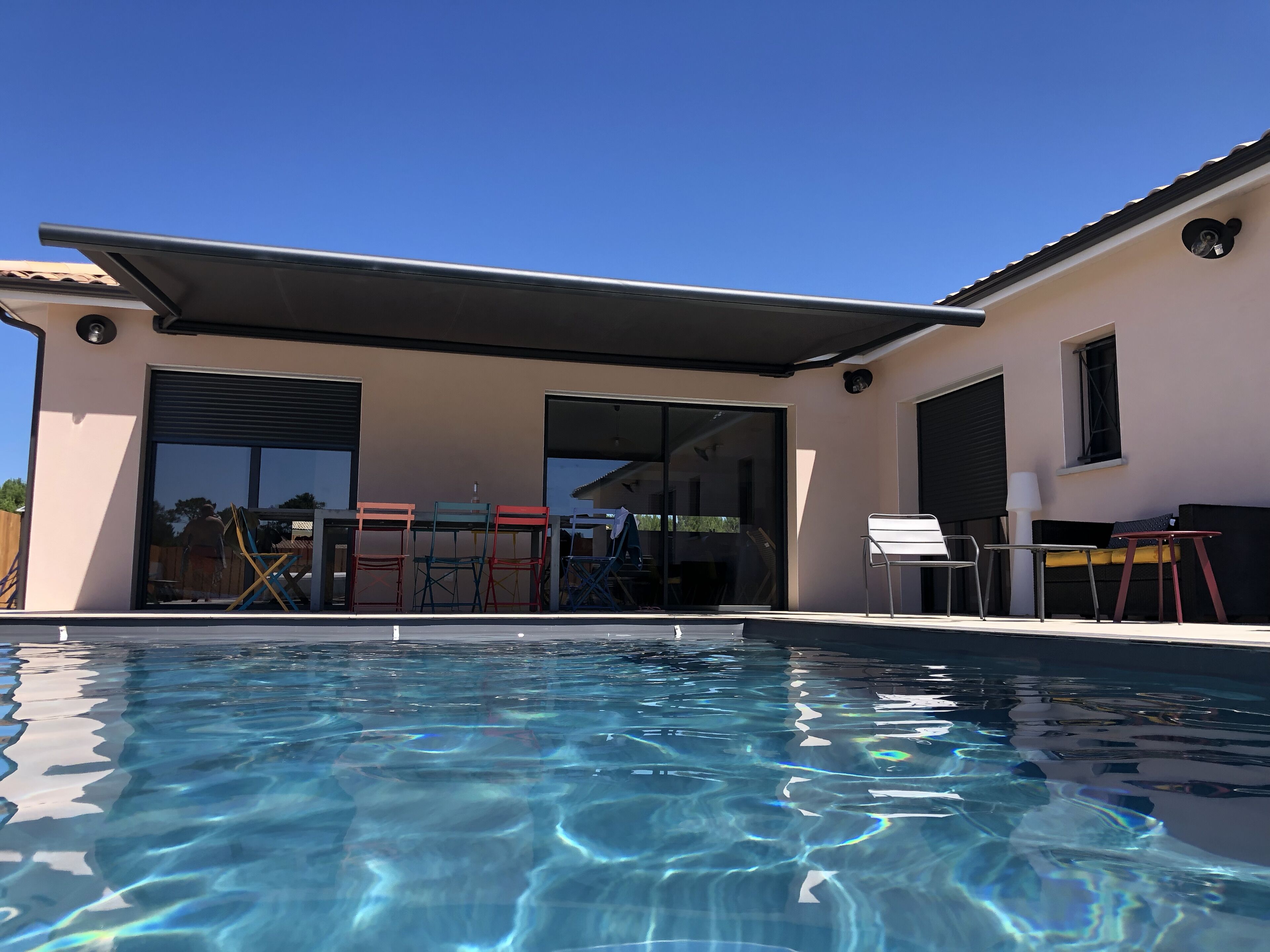 A modern house with a swimming pool, large glass doors, and outdoor furniture.