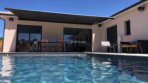 A modern house with a swimming pool, large glass doors, and outdoor furniture. - Seaside villa with large pool and terrace (Vendays-Montalivet)