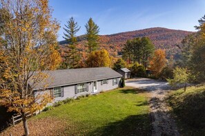Situated in a rural setting, this property features a well-maintained lawn and a gravel driveway leading to the entrance.
