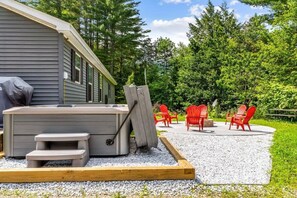 Relax in the serene outdoor patio, featuring a hot tub and comfortable seating area.