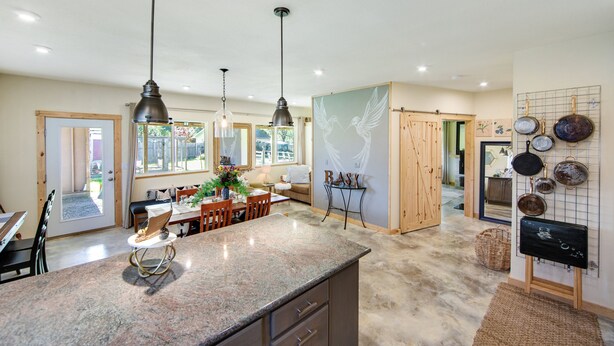 A spacious kitchen with granite countertops, pendant lighting, and a dining area with wooden furniture. - Artisan Boho, Equine Too, Farm Fresh Eggs, Spa, Vino & Views! (Sebastopol)