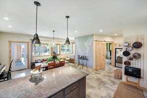 A spacious kitchen with granite countertops, pendant lighting, and a dining area with wooden furniture. - Artisan Boho, Equine Too, Farm Fresh Eggs, Spa, Vino & Views! (Sebastopol)