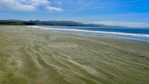 A wide sandy beach with gentle waves, a clear sky, and distant hills. - Artisan Boho, Equine Too, Farm Fresh Eggs, Spa, Vino & Views! (Sebastopol)