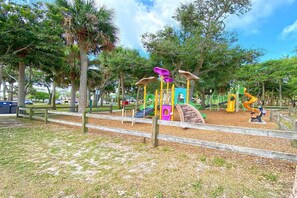 A playground with various play structures, surrounded by trees and a wooden fence. - Newly Furnished, Solar Heated pool, Game room, 10 mins from Beach (Sebastian)