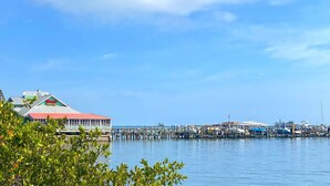A waterfront property with a dock extending into the water, a building with a red roof, and a clear blue sky. - Newly Furnished, Solar Heated pool, Game room, 10 mins from Beach (Sebastian)