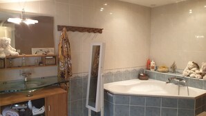 A modern bathroom with a glass shower enclosure, a large bathtub, and a vanity with a mirror. - Character house (PUIMISSON)