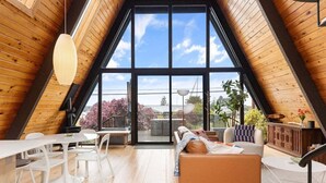 A modern loft with a large skylight, wooden interior, and a cozy seating area.