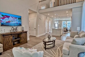 A spacious living room with a television, a wooden cabinet, a round coffee table, and a sofa.