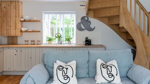 Une cuisine moderne avec des meubles en bois, une étagère intégrée et une fenêtre agrémentée de plantes.