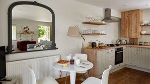 Une cuisine moderne avec des meubles blancs, un plan de travail en bois et un coin repas avec des chaises blanches.