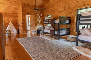 Cozy cabin-style room with a rustic charm, featuring a set of bunk beds and a plush area rug.