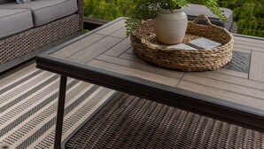 A balcony with a wicker sofa, a small table, and a potted plant. - Luxury 5 BR Cabin with Hot Tub and Views!  (Townsend)