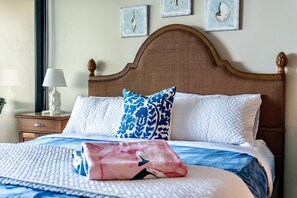A neatly made bed with a patterned bedspread, a decorative pillow, and a bedside table with a lamp. - WOW! What a view!!! Oceanfront Condo in Ka’anapali! King Bed! (Lahaina)