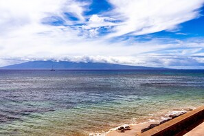 A coastal view with clear skies, a distant mountain, and a boat on the water. - WOW! What a view!!! Oceanfront Condo in Ka’anapali! King Bed! (Lahaina)