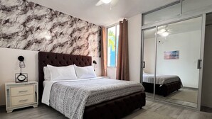 Ein Schlafzimmer mit Bett, Nachttisch, Kleiderschrank und einem Fenster mit Vorhängen.