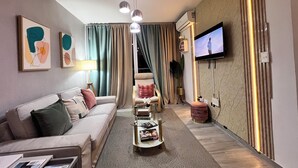 Ein modernes Wohnzimmer mit einer Couch, einem Couchtisch, einem Fernseher und einer Pflanze.