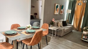 Ein modernes Wohnzimmer mit Essbereich, ausgestattet mit einer Couch, einem Couchtisch und einem Esstisch mit Stühlen.