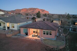 A residential area with houses, a patio with outdoor furniture, and a mountain in the background.