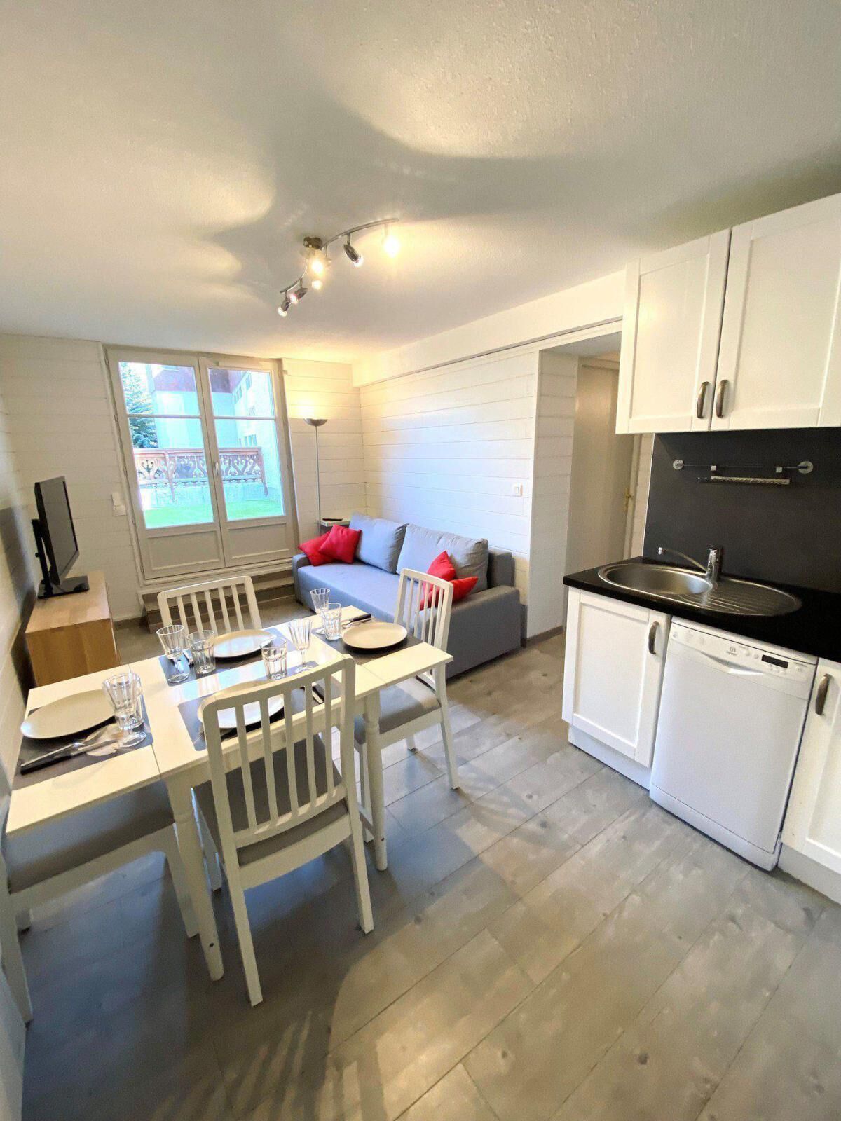 A compact kitchen with a dining area, white cabinets, a black countertop, and a view of the outside.