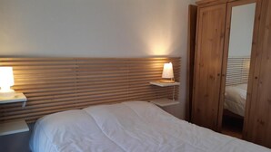 Una camera da letto con un letto, lampade da comodino, una testiera in legno e un armadio.