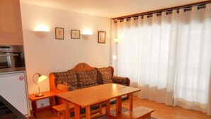 Un ambiente compatto con un tavolo da pranzo in legno, una poltrona e un angolo cottura.