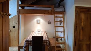 A cozy room with a wooden bunk bed, a table with a checkered tablecloth, and a ladder. - 100m from ski slopes, 4th floor, tv, ski locker, 44m², Les 2 Alpes (Les Deux Alpes)