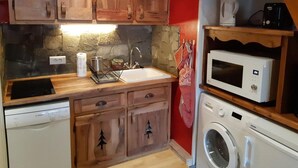 A compact kitchen with wooden cabinets, a stone backsplash, a Bosch dishwasher, a microwave, and a washing machine. - 100m from ski slopes, 4th floor, tv, ski locker, 44m², Les 2 Alpes (Les Deux Alpes)