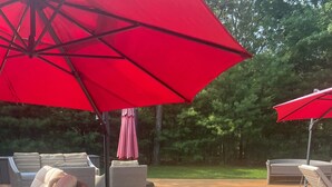 Een houten terras met rieten meubilair en rode parasols.