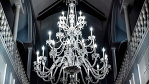 A grand chandelier in a hallway with a high ceiling and dark walls. - Smithmore Castle (Spruce Pine)