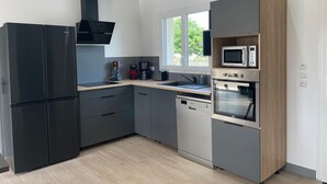 Une cuisine moderne avec un réfrigérateur noir, un four à micro-ondes et un four traditionnel.