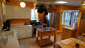 Eine Küche mit weißen Schränken, einem Holztisch und einem Edelstahlkühlschrank.