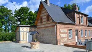 Un bâtiment à deux étages, construit en briques, avec un toit à pignon, un petit abri attenant et une allée pavée.